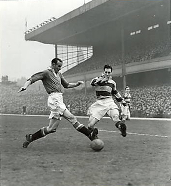 London: J. Lewis, Walthamstow Avenue's centre-forward - who scored two goals in the match - and Chilton, Manchester United's centre-half (plain shirt), in a tussle for the ball in front of the goalmouth in the fourth round replay match of the Football Association Challenge Cup, played at Highbury. February 5th 1953. (Topham).